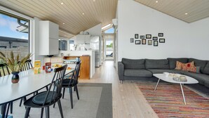 A modern living space with a dining area, kitchen, and a sofa.
