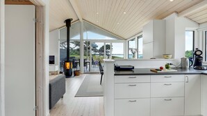 A modern kitchen with white cabinetry, a central island, and a view of the outdoors.
