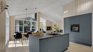 A modern kitchen with a central island, built-in appliances, and a dining area with natural light.