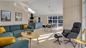 A modern living room with a sofa, coffee table, and a dining area with chairs and a table.