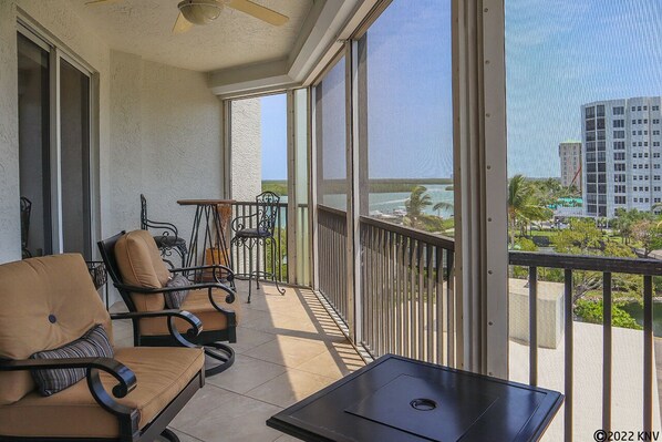A balcony with outdoor furniture, a table, and a view of a cityscape and water.