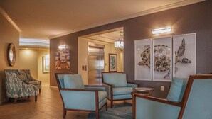 A lobby with a reception desk, a seating area with chairs, a large mirror, and artwork on the walls. - GRAND EXECUTIVE 3B/3B WATERSIDE 246 ISLAND CONDO (Fort Myers Beach)