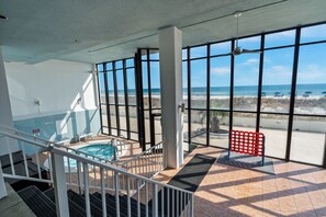 A spacious indoor area with a pool, large windows offering a view of the beach, and a red seating area.