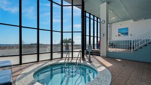 Une grande piscine intérieure offrant une vue dégagée sur l’océan grâce à de larges baies vitrées.
