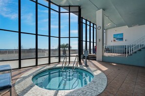 A large indoor swimming pool with clear views of the ocean through expansive windows.