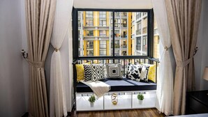 Ein Zimmer mit Fensterbank, dekorierten Kissen, einem kleinen Tisch mit Pflanzen und Vorhängen.