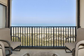 Ein Balkon mit zwei Stühlen mit Blick auf den Strand.