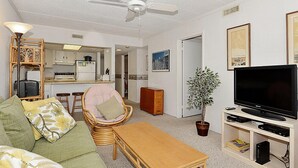 A compact living space with a kitchenette, a dining area, a seating area with a sofa and a chair, a television, and a potted plant. - Bonaire 404-Oceanfront 126th St, Free WiFi, Elev, W/D, AC (Ocean City)