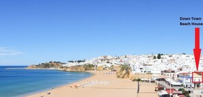 Une ville côtière avec une plage, une flèche rouge indiquant un bâtiment portant l’inscription « Down Town Beach House ».
