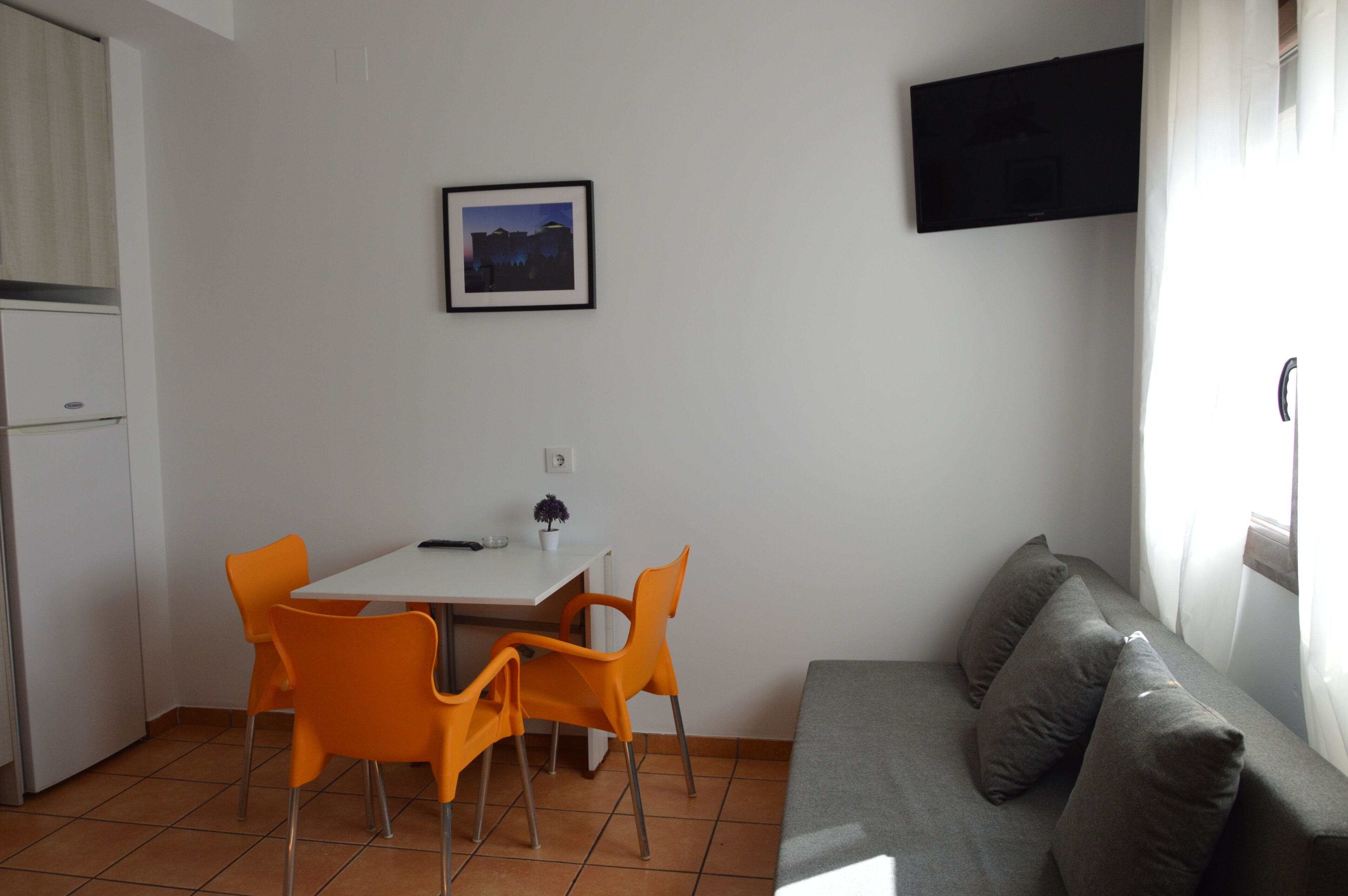 Un espacio habitable compacto con comedor, sofá y televisor montado en la pared.