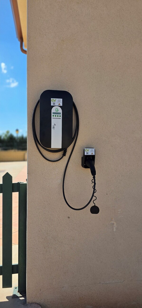 A wall-mounted EV charging station with a cable connected to a wall socket.