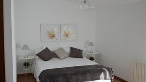 A neatly arranged bedroom with a bed, two bedside tables, a radiator, and two wall-mounted artworks.