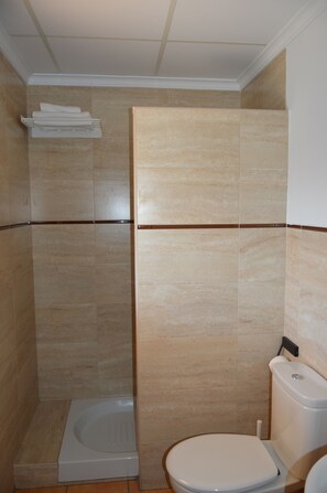 A bathroom with a toilet, a shower stall, and a towel rack.