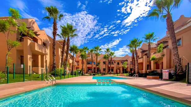 A swimming pool surrounded by palm trees and hotel buildings with balconies. - Awesome apartment in Los Alcázares (Los Alcázares)