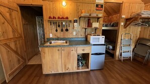Een compacte keuken met houten kastjes, een spoelbak, een magnetron en een kleine koelkast. Er zijn bordjes met een rook- en dampverbod.