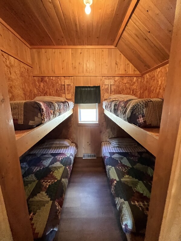 A cabin with two bunk beds, a small window, and a light fixture on the ceiling.