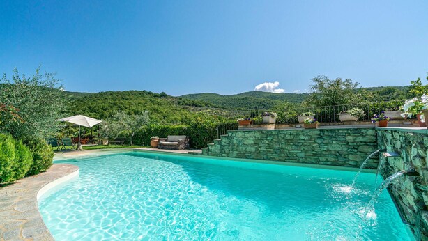 A clear blue pool with stone steps leading into it, surrounded by lush greenery and a view of hills in the background. - Gorgeous home in Arezzo with kitchen (Arezzo)