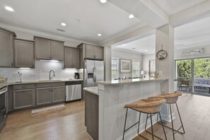 Uma cozinha moderna com armários cinza, eletrodomésticos de aço inoxidável e uma ilha central com banquetas.