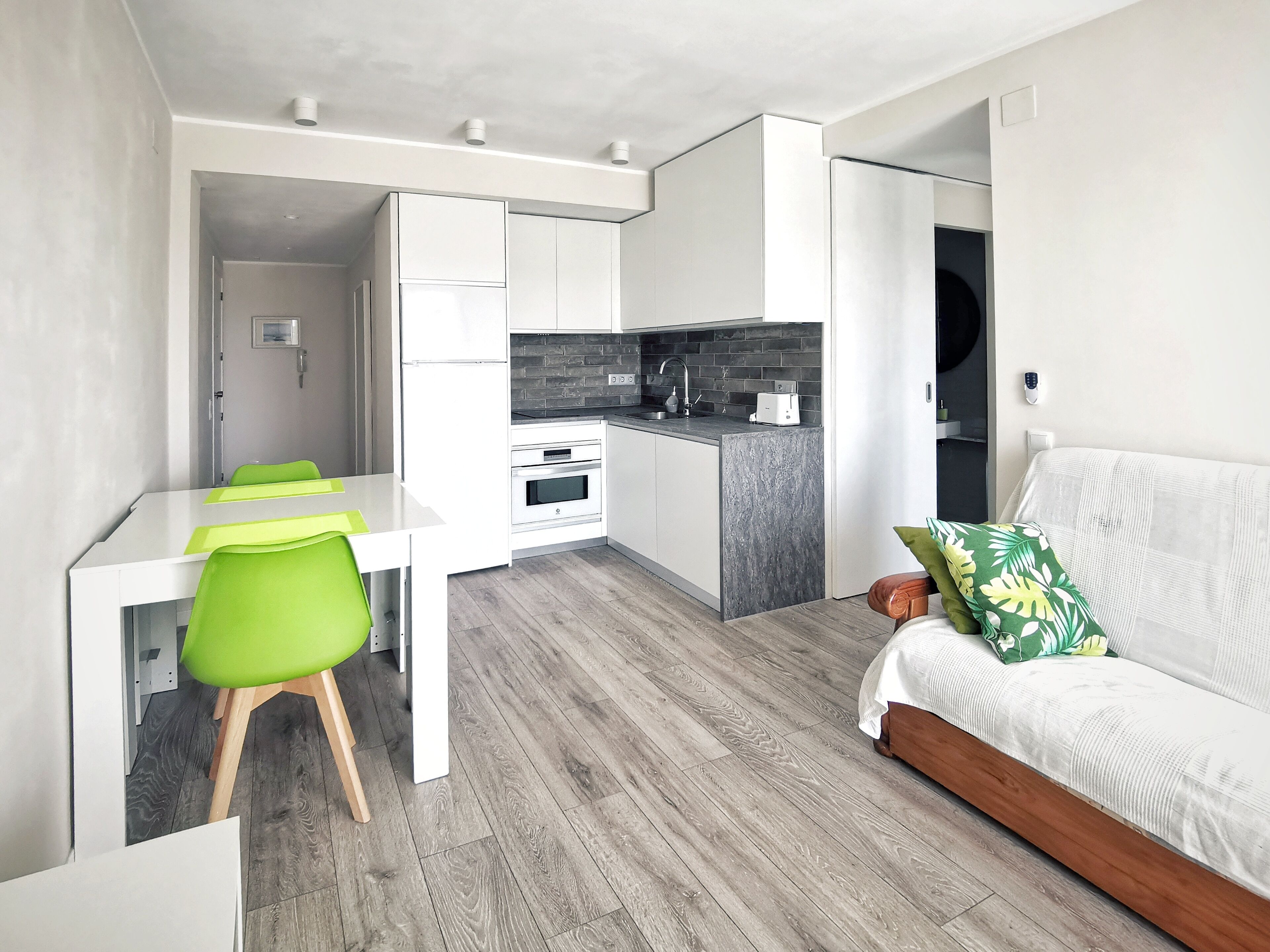 Un espacio habitable compacto con kitchenette, comedor y sofá.
