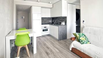 Un espacio habitable compacto con kitchenette, comedor y sofá.