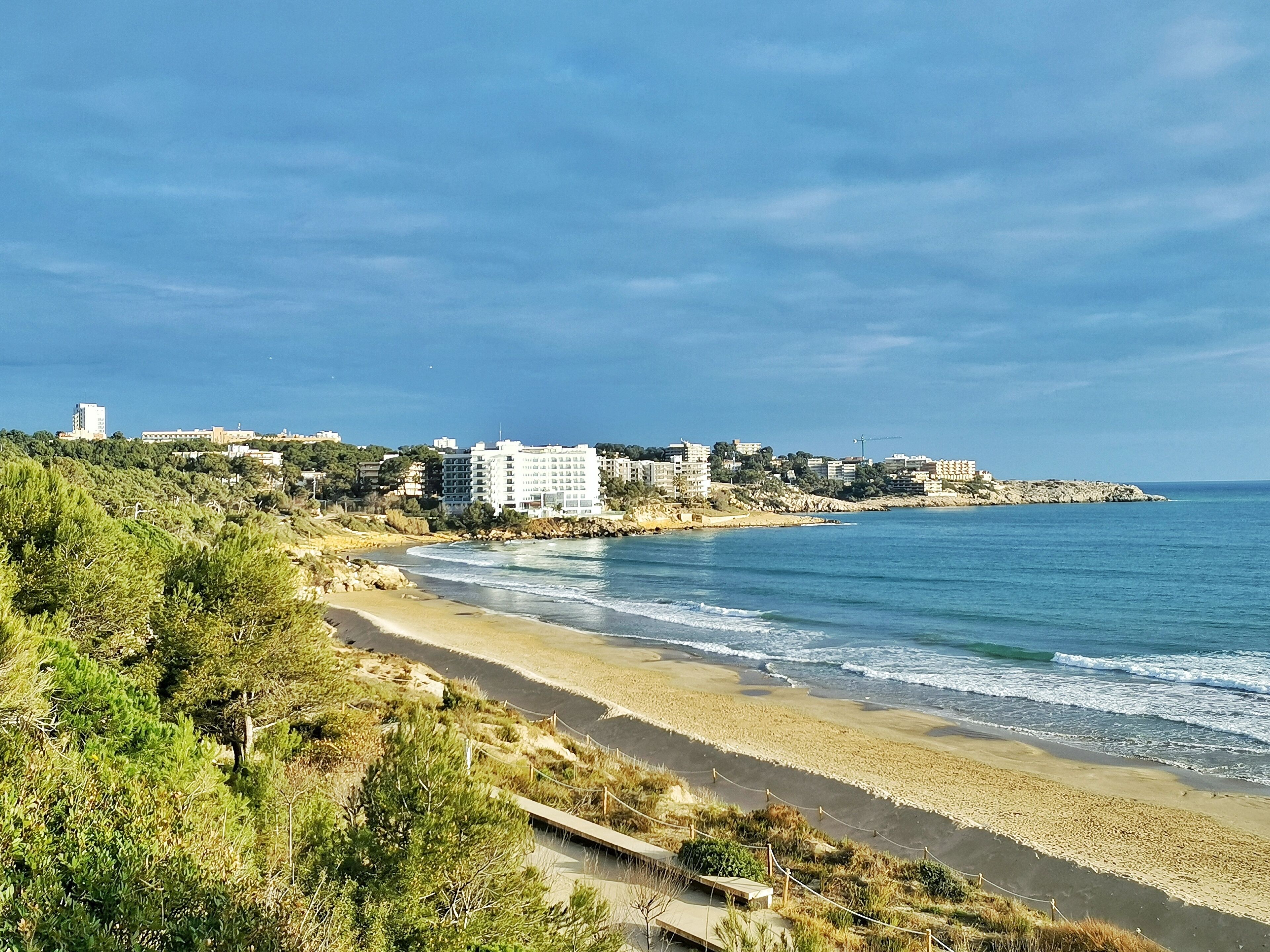 Une vue sur la côte, avec une plage, des bâtiments et un ciel dégagé.