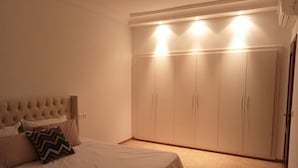 Une chambre à coucher comprenant un lit, une tête de lit, une armoire et un sol recouvert de moquette.
