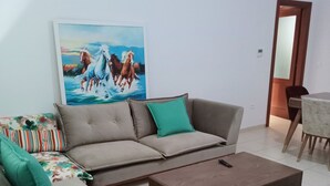 Un salon avec un canapé d’angle, une table basse et un tableau accroché au mur.