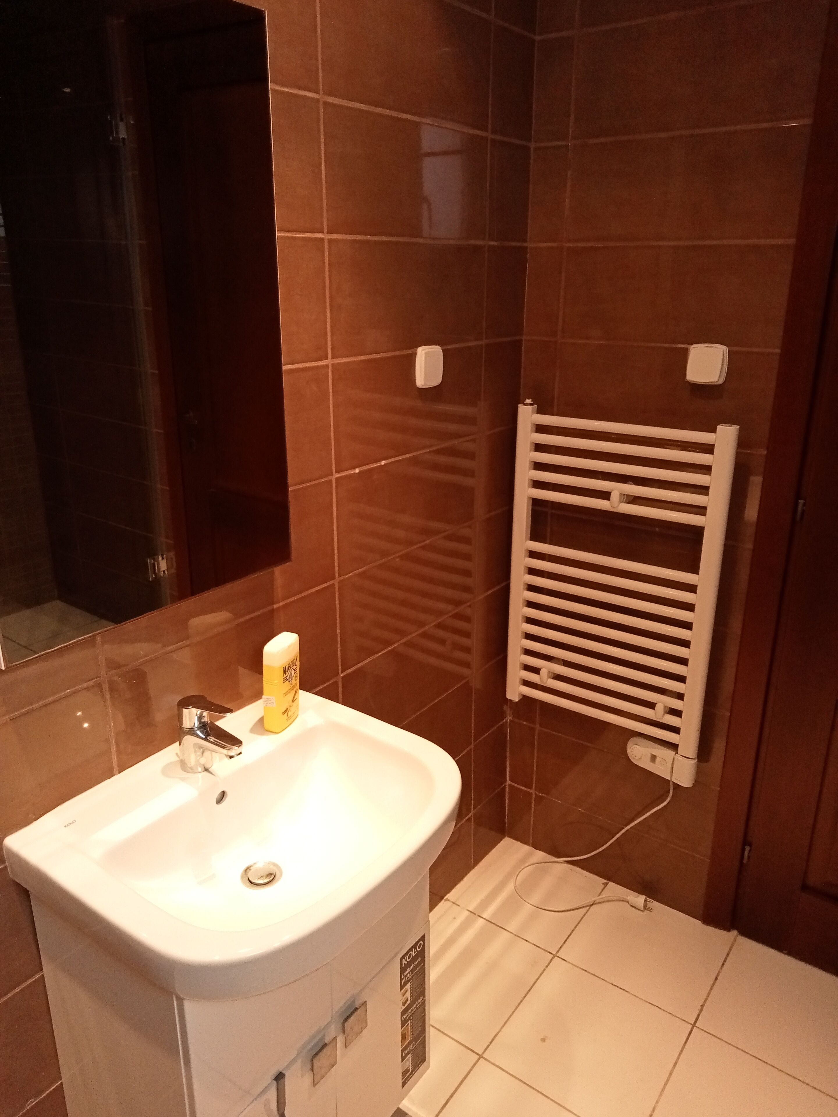 Une salle de bain avec un lavabo blanc, un miroir et un porte-serviettes.