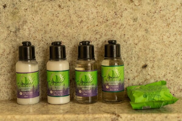 Three bottles of shampoo and a green packet on a countertop. - Be Caju Hotel (Cajueiro da Praia)