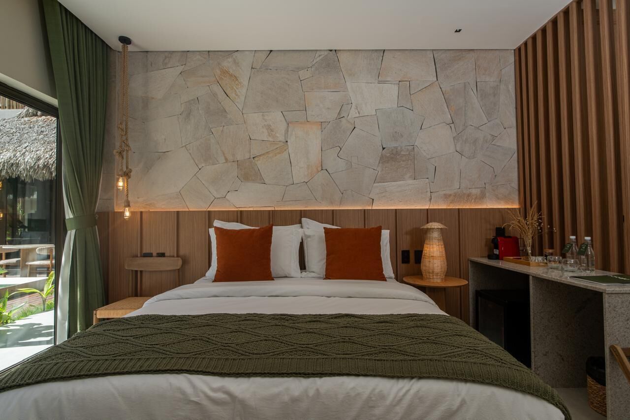 Un dormitorio moderno con pared de piedra, cabecero de madera y una mesita de noche con lámpara.