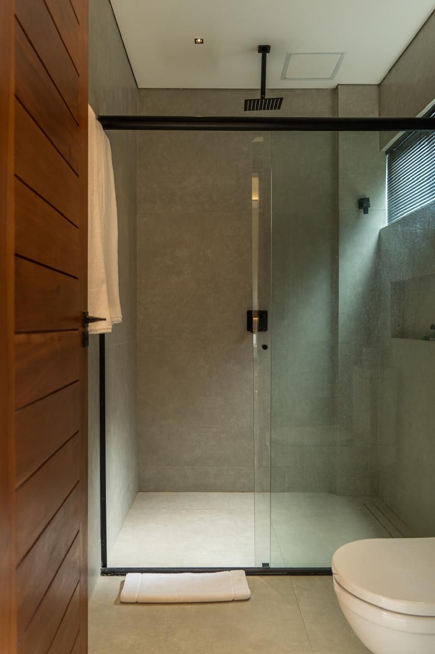 A modern bathroom with a glass-enclosed shower, a wooden panel wall, and a white toilet.
