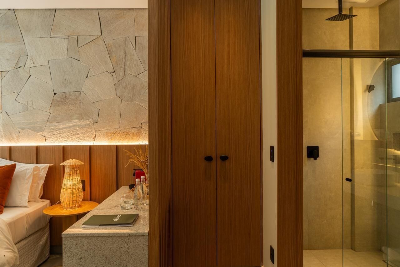 Ein modernes Hotelzimmer mit einer Steinwand, einem Holzschrank und einer Duschkabine aus Glas.