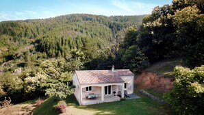 Una casa de un piso con tejado de tejas, rodeada de un césped cuidado y un bosque frondoso.