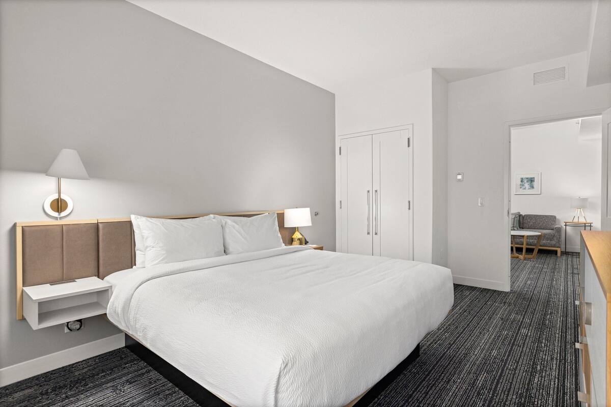 Ein modernes Hotelzimmer mit einem großen Bett, Nachttischen, einem Schreibtisch und einem Sessel.