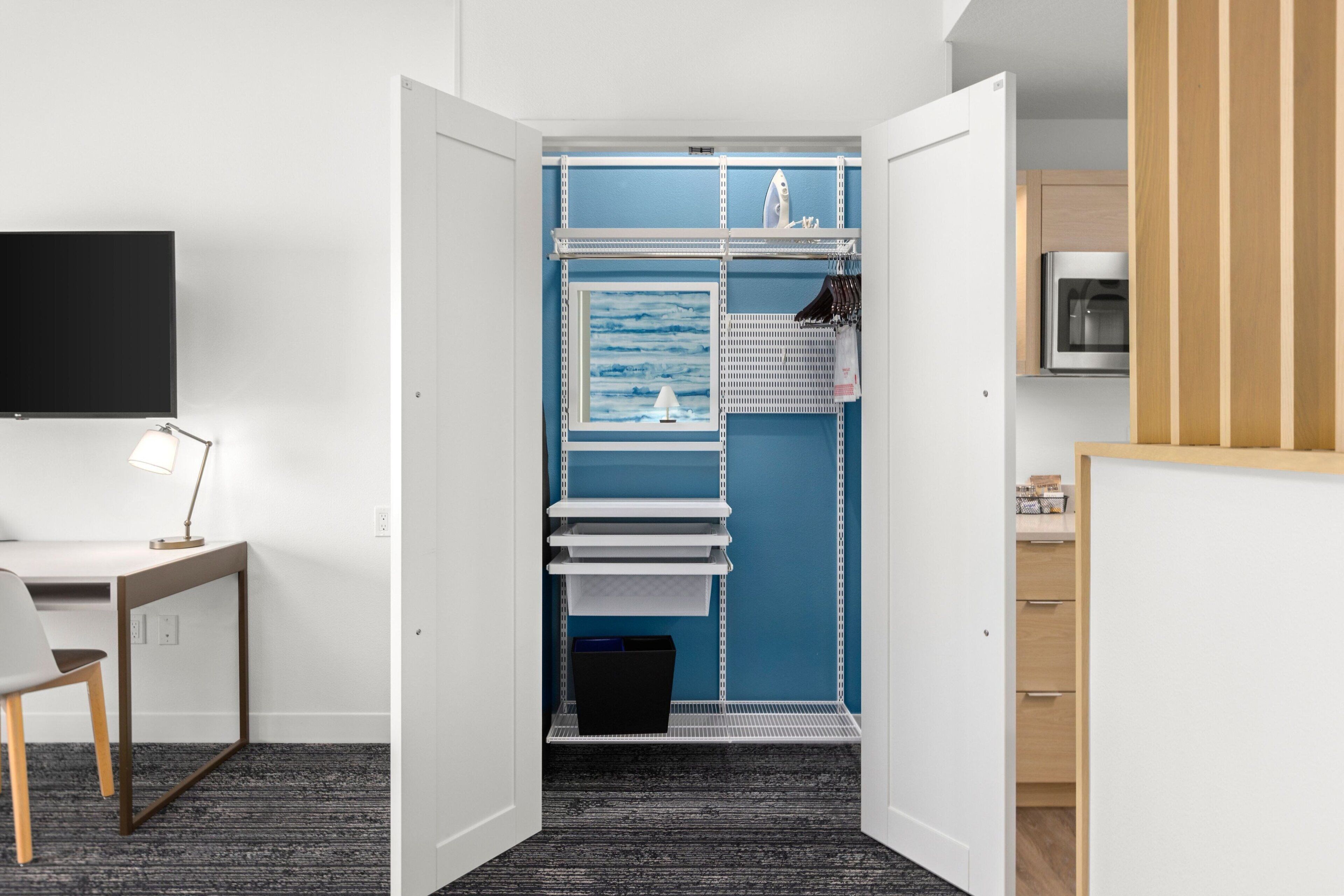 A modern room with a desk, chair, and a built-in shelving unit with a blue accent wall.