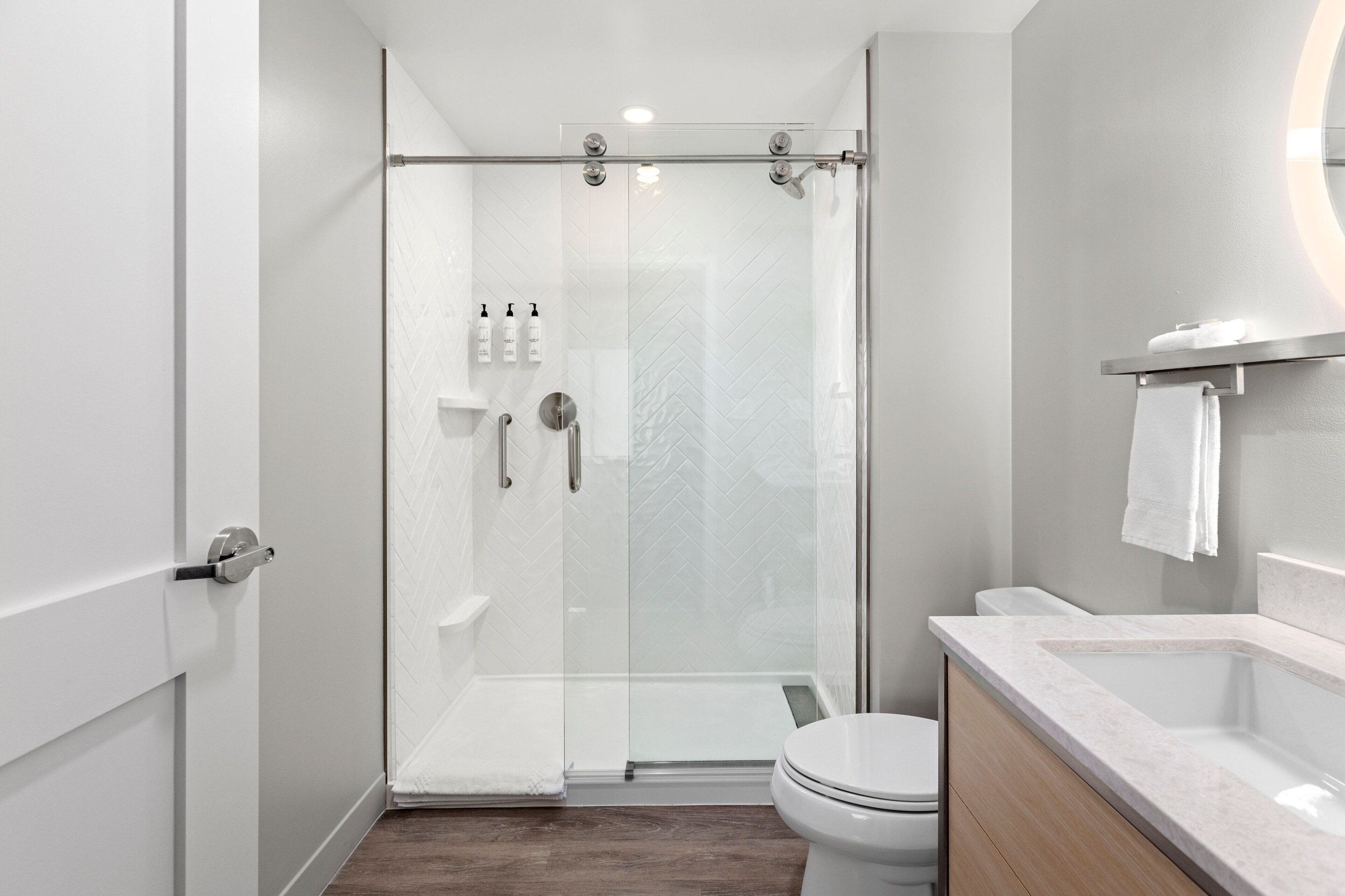Un baño moderno con ducha de vidrio, inodoro blanco y lavamanos de mármol.