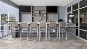 An outdoor bar area with multiple seating arrangements, a counter, and a large screen.