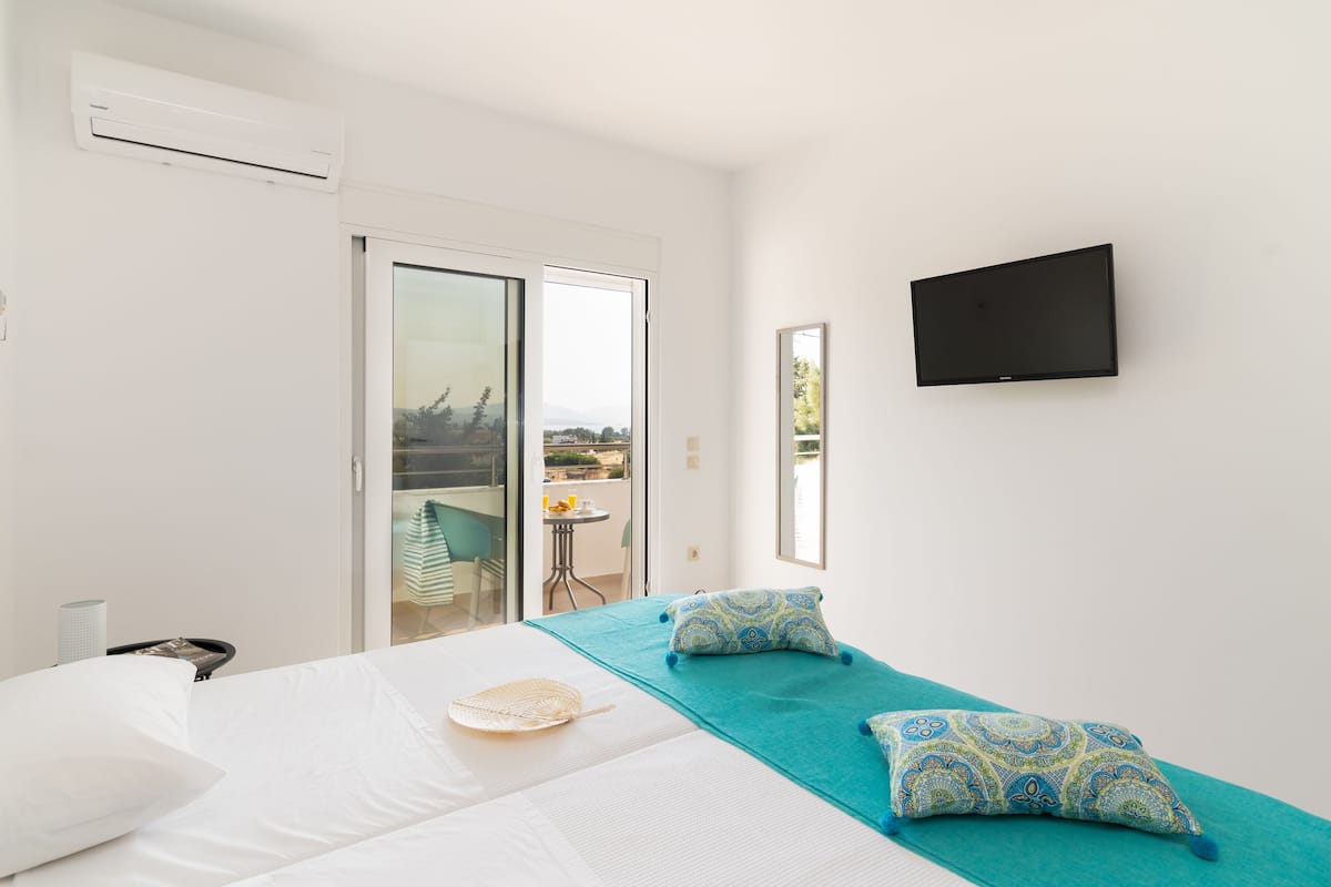 Ein Hotelzimmer mit Bett, einem an der Wand montierten Fernseher und Blick ins Freie.