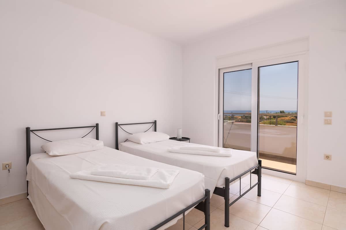 Ein Zimmer mit zwei Betten, einem Balkon mit Blick und einer Schiebetür.