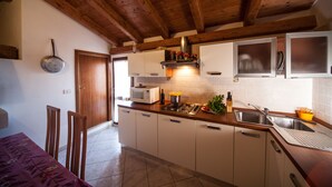 A kitchen with wooden beams, white cabinets, a microwave, and a gas stove.