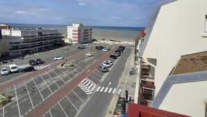 Un parcheggio con diverse auto, un attraversamento pedonale e vista sulla spiaggia e sull'oceano.