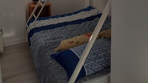 Camera con letto a castello, finestra, un piccolo tavolo e un salvagente appeso al muro.