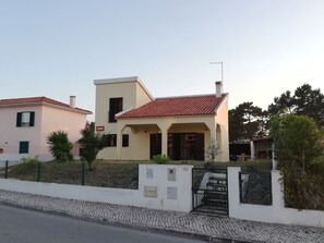 A two-story building with a red-tiled roof and a small porch.