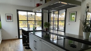 A modern kitchen with a large island, stainless steel appliances, and a view of the outdoors. - Magnifique Villa D'architecte A 10 Minutes D'avignon (Tavel)