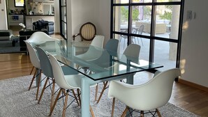 A modern dining area with a glass table and chairs, a chandelier, and a view of the outdoor patio through large windows. - Magnifique Villa D'architecte A 10 Minutes D'avignon (Tavel)