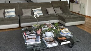 A modern living room with a sectional sofa, a glass coffee table with magazines, a potted plant, and a staircase leading to an upper level. - Magnifique Villa D'architecte A 10 Minutes D'avignon (Tavel)