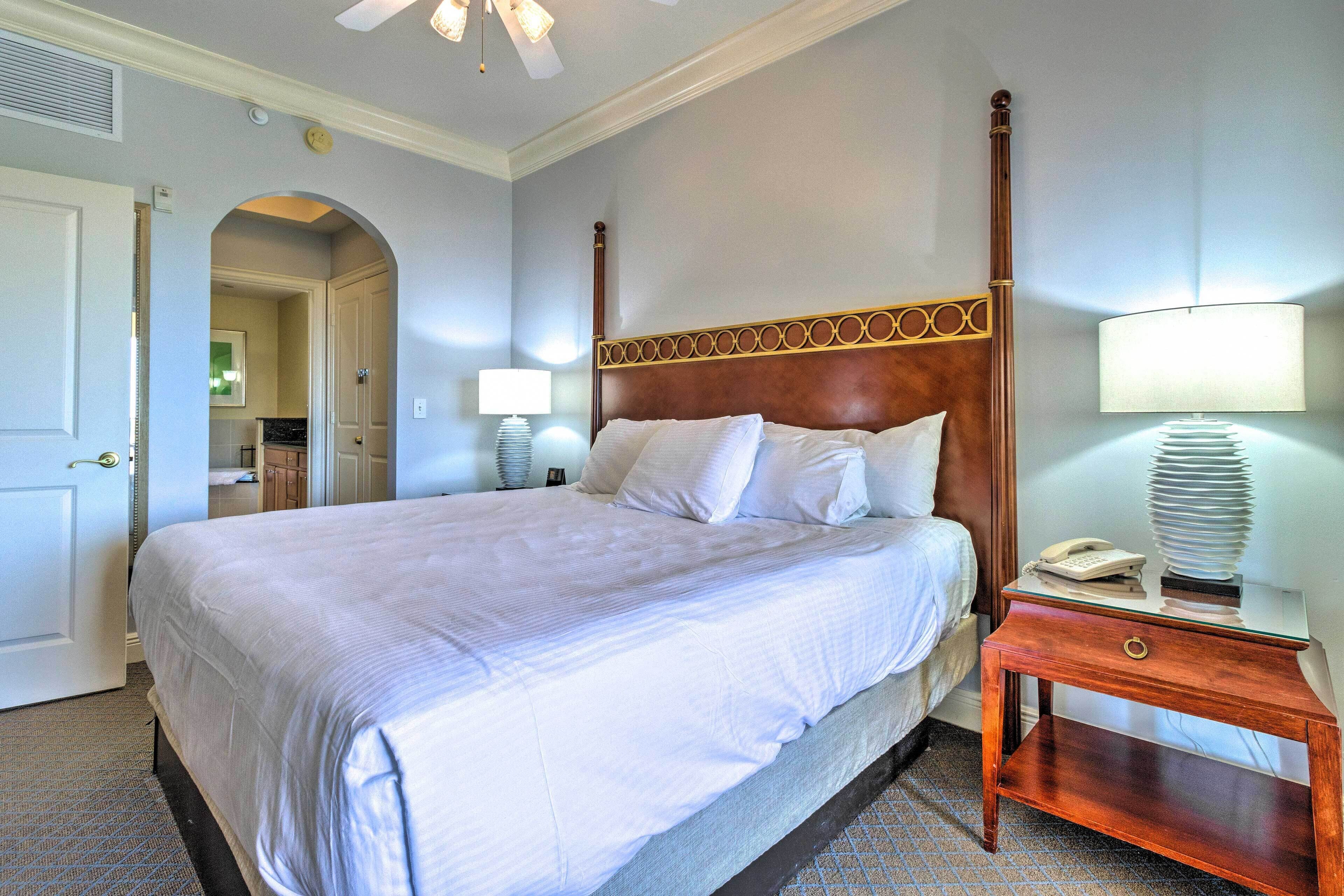 A neatly made bed with a wooden headboard, a bedside lamp, and a telephone on a nightstand.