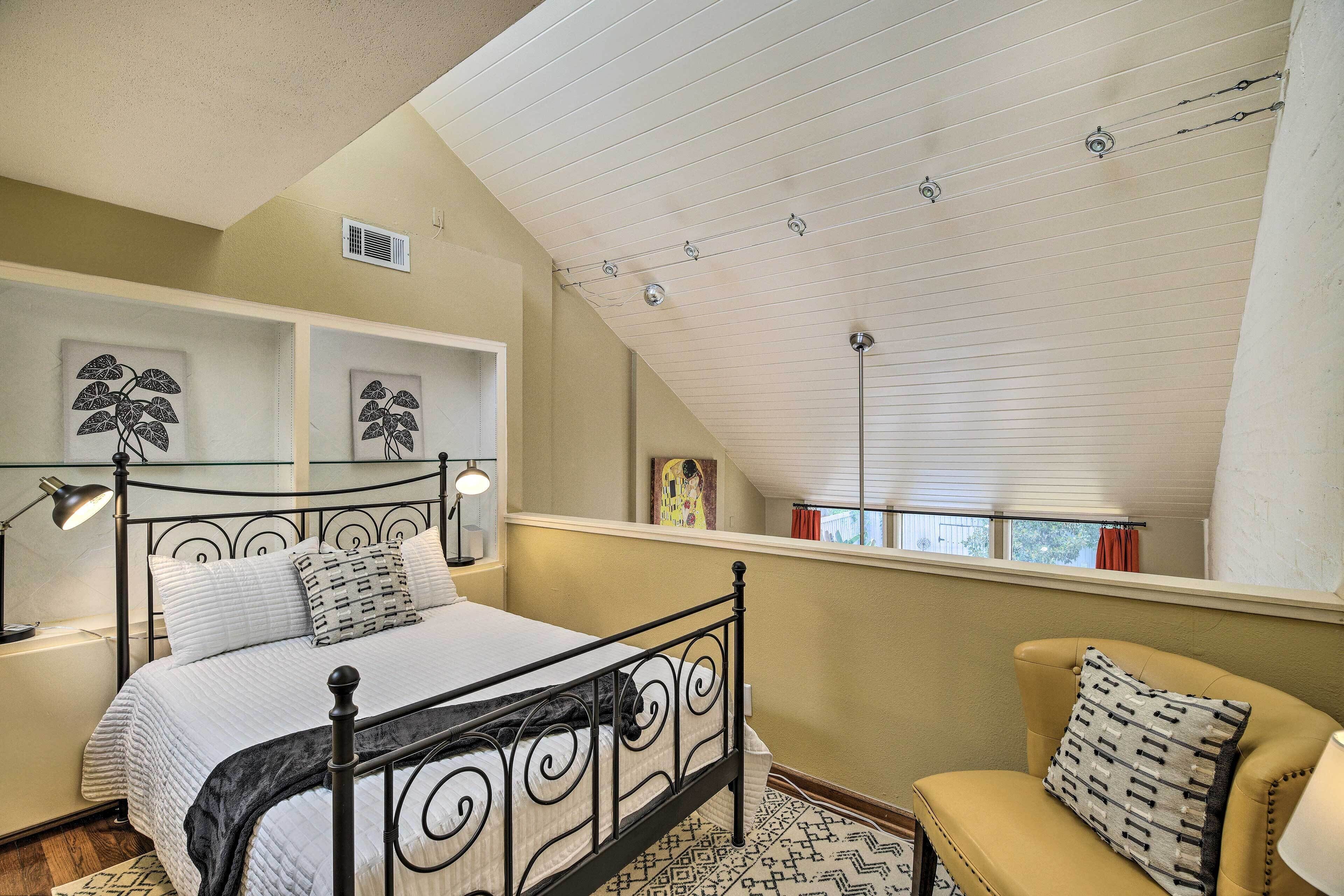 A bedroom with a bed, a chair, a window, and a ceiling fan.