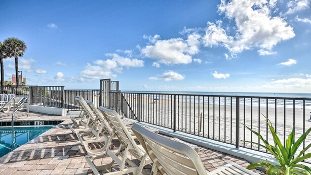 A poolside area with lounge chairs and a pool, overlooking a beach. - Airy Oceanfront Condo: Steps to Daytona Beach (Daytona Beach)