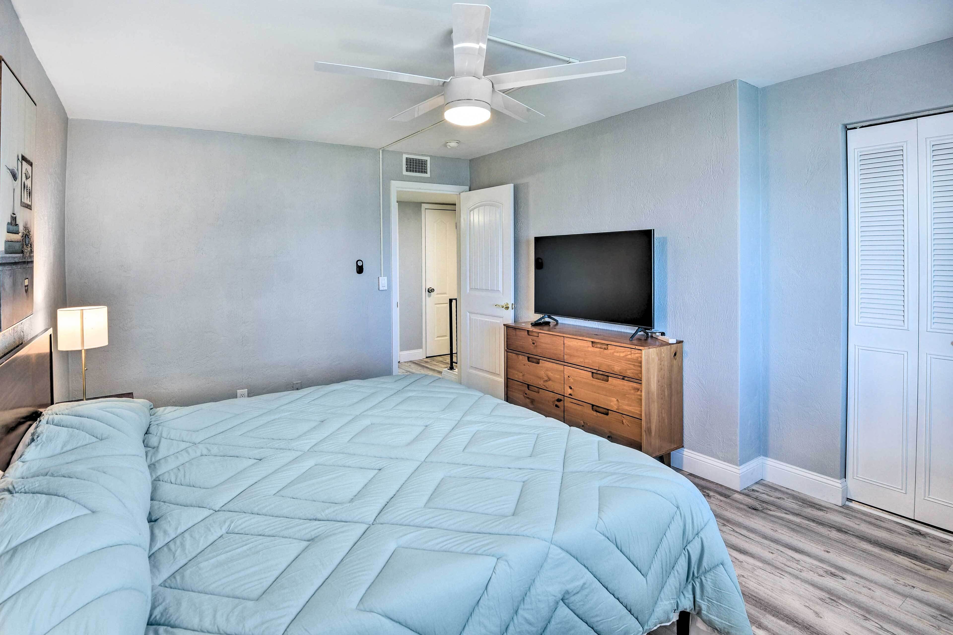 Quarto com cama, ventoinha no teto, cômoda e televisão.